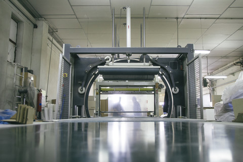 Silhouetten von Mitarbeitern hinter einer Verpackungsmaschine in einer Fabrik, lizenzfreies Stockfoto