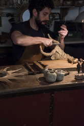 Kunsthandwerker beim Flechten eines Stierkopfes aus Korbgeflecht in seiner Werkstatt - ABZF000570