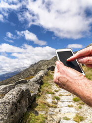 Spanien, Sierra de Gredos, Wanderer mit Mobiltelefon auf dem Weg - LAF001640