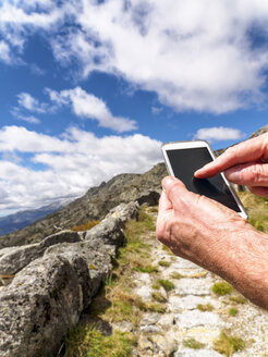 Spanien, Sierra de Gredos, Wanderer mit Mobiltelefon auf dem Weg - LAF001640