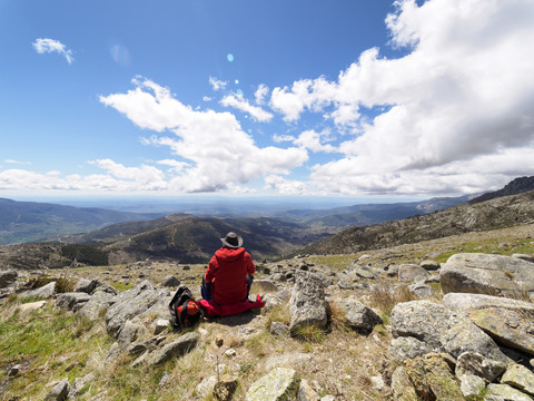 Spanien, Sierra de Gredos, Wanderer in Berglandschaft sitzend, lizenzfreies Stockfoto