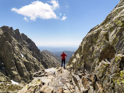 Spain, Sierra de Gredos, hiker standing on rock in mountainscape - LAF001648