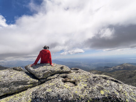 Spanien, Sierra de Gredos, Wanderer sitzt auf einem Felsen in einer Berglandschaft - LAF001654