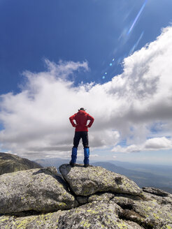 Spain, Sierra de Gredos, hiker standing on rock in mountainscape - LAF001655