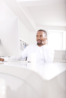 Porträt eines Geschäftsmannes, der am Schreibtisch im Büro telefoniert - MFRF000624