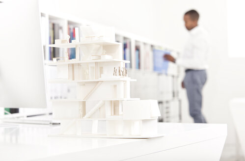 Architekturmodell auf einem Schreibtisch in einem Büro mit einem Mann im Hintergrund - MFRF000641
