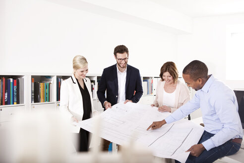 Vier Kollegen besprechen einen Bauplan in einem Büro - MFRF000645