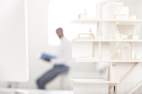 Architectural model on desk in an office with reading man in the background - MFRF000647