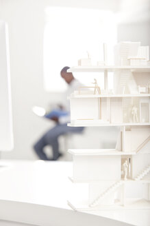 Architekturmodell auf einem Schreibtisch in einem Büro mit einem Mann im Hintergrund - MFRF000650
