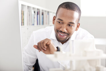 Portrait of smiling man in the office using his smartwatch - MFRF000654