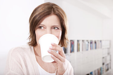 Porträt einer Frau, die im Büro Kaffee zum Mitnehmen trinkt - MFRF000671