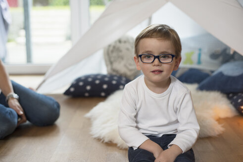 Kleiner Junge mit Brille sitzt auf dem Boden im Kinderzimmer - LFOF000228