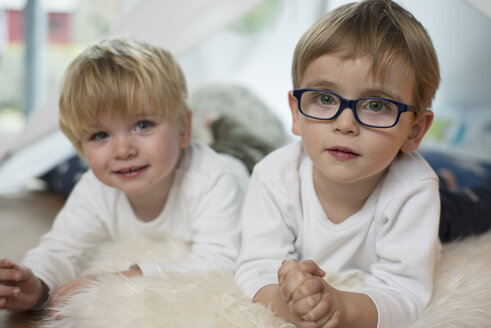 Zwei kleine Jungen spielen zu Hause, auf einem Schaffell liegend - LFOF000230