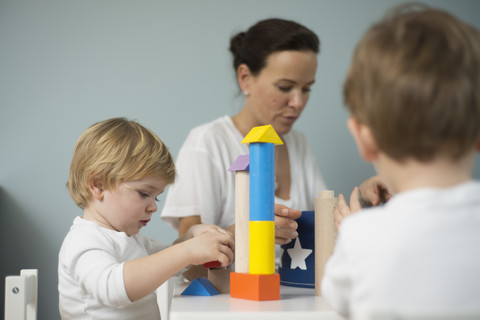 Mutter und Söhne spielen mit Bauklötzen, lizenzfreies Stockfoto