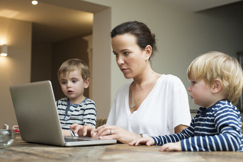 Mutter benutzt Laptop, während ihre Söhne neben ihr sitzen - LFOF000245