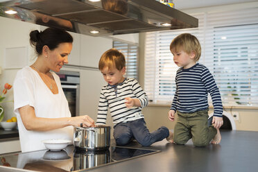 Zwei Jungen beobachten ihre Mutter bei der Zubereitung von Essen - LFOF000247