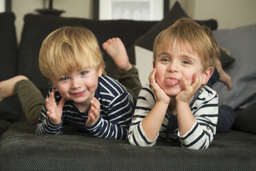 Two little boys playing at home, lying on couch - LFOF000252