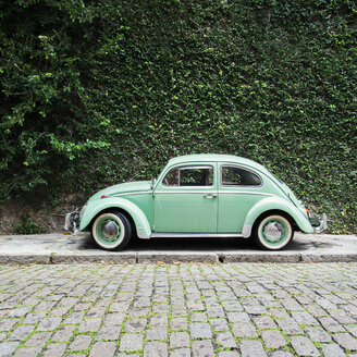 Brazil, Rio de Janeiro - Green vintage car in front of overgrown green wall - JUBF000160