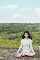 Young woman meditating on the cliff - BZF000288