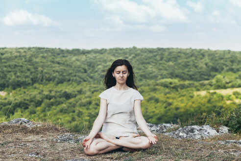 Junge Frau meditiert auf einer Klippe - BZF000289