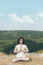 Young woman meditating on the cliff - BZF000290