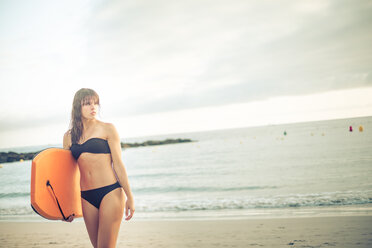 Spanien, Teneriffa, junge Frau mit Schwimmbrett am Strand - SIPF000517