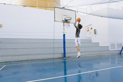 Junger Mann spielt Basketball auf einem Deck eines Kreuzfahrtschiffs, lizenzfreies Stockfoto