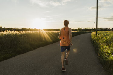 Germany, young man jogging, against the sun - UUF007379