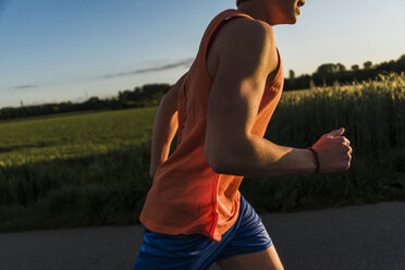 Deutschland, junger Mann beim Joggen, Arm, im Abendlicht - UUF007382