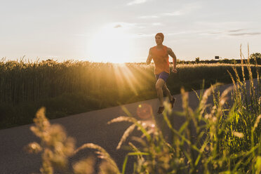 Deutschland, junger Mann beim Joggen, gegen die Sonne - UUF007386