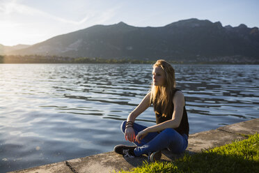 Italien, Lecco, nachdenkliches Teenager-Mädchen am Ufer des Sees - MRAF000061