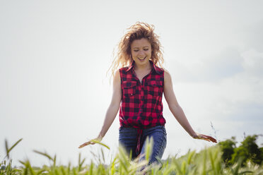 Happy woman walking in the field - GIOF001128