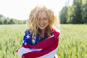 Porträt einer lächelnden Frau mit amerikanischer Flagge in der Natur - GIOF001140