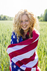 Porträt einer lächelnden Frau mit amerikanischer Flagge in der Natur - GIOF001141