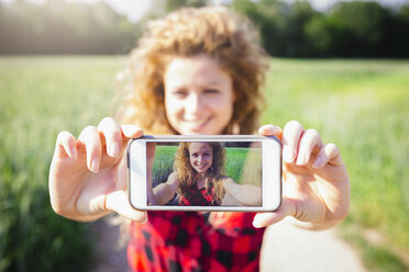 Selfie einer lächelnden Frau auf dem Display ihres Smartphones - GIOF001145