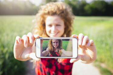 Selfie of smiling woman on display of her smartphone - GIOF001145