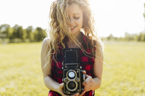 Lächelnde Frau mit Retro-Kamera in der Natur, lizenzfreies Stockfoto