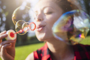 Woman blowing soap bubbles, close-up - GIOF001158