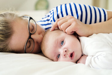 Mother with baby lying on bed - HAPF000455