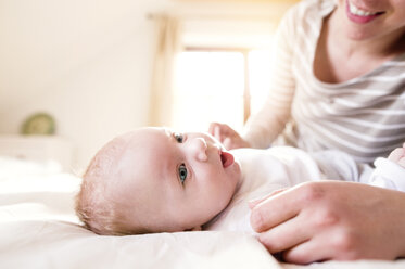 Mother with baby lying on bed - HAPF000476