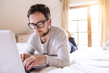 Mann auf dem Bett liegend mit Laptop - HAPF000481