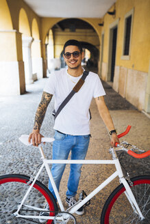 Junger Mann mit einem Fahrrad in der Stadt - GIOF001159