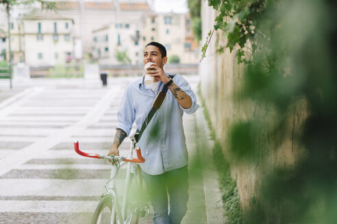 Junger Mann zu Fuß mit einem Fahrrad in der Stadt - GIOF001193