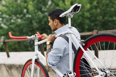 Junger Mann trägt ein Fahrrad - GIOF001195