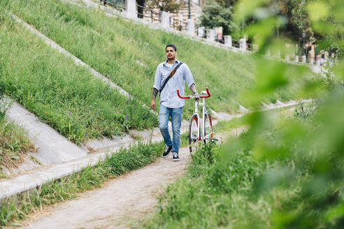 Junger Mann geht mit einem Fahrrad auf einem Weg - GIOF001198