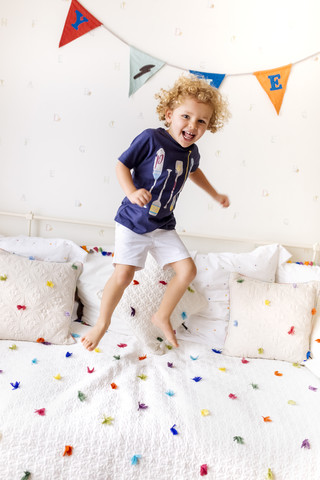 Porträt eines lachenden kleinen Jungen, der auf die Couch springt, lizenzfreies Stockfoto