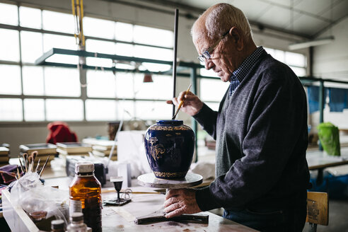 Senior man decorating ceramic vase in his spare time - JRFF000683