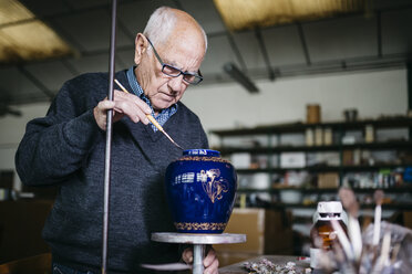 Älterer Mann dekoriert in seiner Freizeit eine Keramikvase - JRFF000684