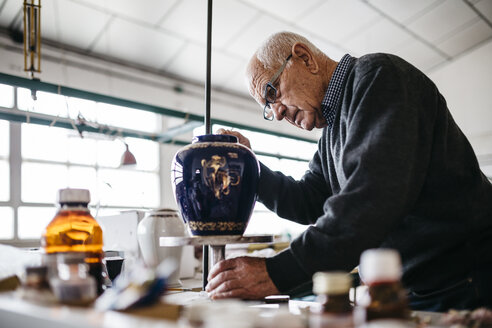 Älterer Mann dekoriert in seiner Freizeit eine Keramikvase - JRFF000685