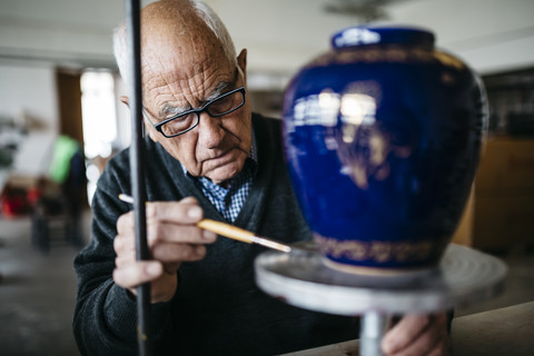 Senior man decorating ceramic vase in his spare time stock photo